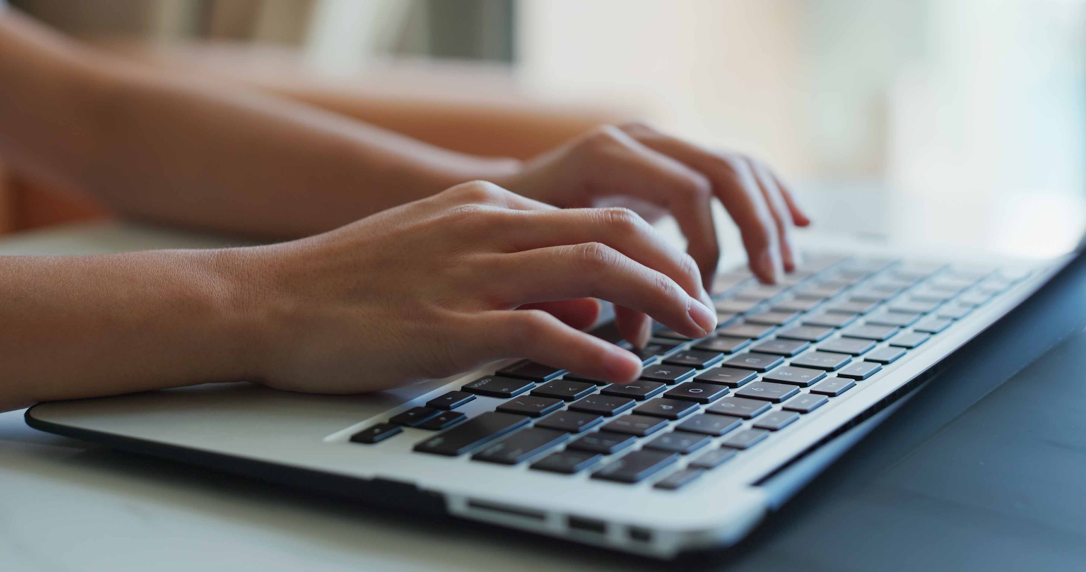 Hands typing on a laptop